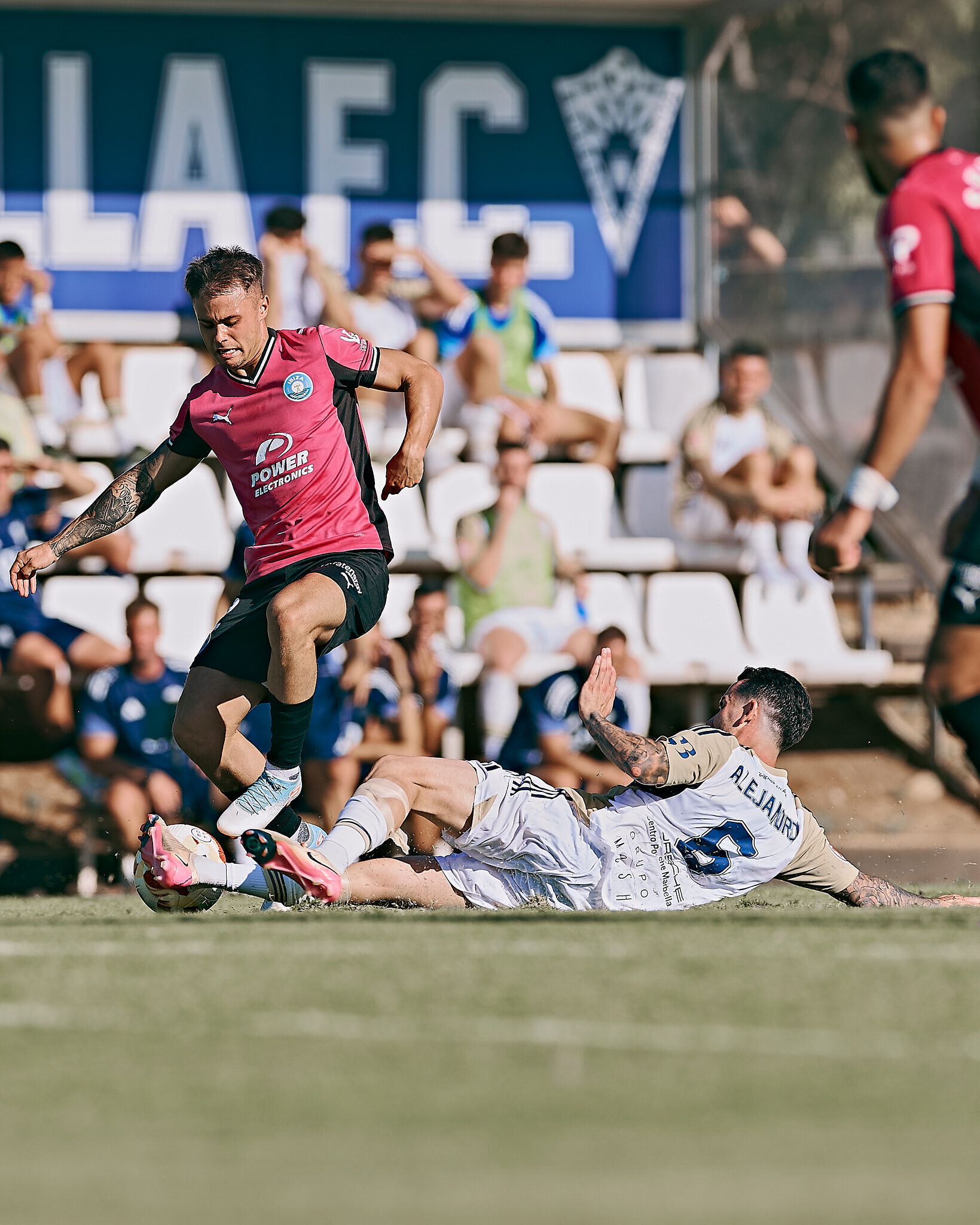 Sergio Díez evita con fuerza una entrada a ras de suelo del jugador malagueño, manteniendo la posesión.